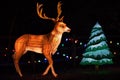 Festive Christmas lights in the shape of deer standing next to a decorated fir tree