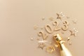 Festive Christmas and New Year background with golden champagne bottle, confetti stars and 2023 numbers