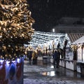 Festive Christmas and New Year& x27;s fair square in the city at night, falling snow, New Year tree and houses with garlands. Royalty Free Stock Photo