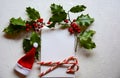 Festive Christmas scene with green holly, two candy canes, Santa hat Royalty Free Stock Photo