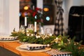 The festive Christmas table is decorated with branches of a Christmas tree, candles and garlands. Cozy home Christmas atmosphere Royalty Free Stock Photo