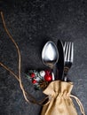 Festive Christmas table place setting with cutlery, pine branche, red berries, rose hip, cone in burlap bag. Winter holidays and Royalty Free Stock Photo