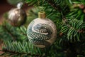 Festive Christmas tree toy ball with drawing green snake close up on a background of fir branch