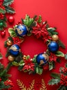Festive Christmas Wreath with Blue Ornaments, Poinsettias and Pine Cones on Vibrant Red Background for Holiday Decor Royalty Free Stock Photo