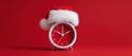 The festive clock adorned with a Santa hat against a red background. AI generated image Royalty Free Stock Photo