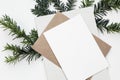 Festive closeup of Christmas blank greeting card, invitation mockup template. Craft envelope, diary and green yew tree