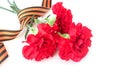 A festive composition with a bouquet of red carnations and a St. George ribbon for the Victory Day on May 9. Royalty Free Stock Photo