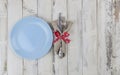Festive composition with empty blue plate and cutlery set on rustic white wooden table. Table settings. Top view