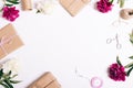 Festive composition of peonies and gifts on a white table