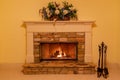 Flower adorned mantle with a fire in the stone fireplace.