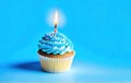 Festive cupcake with a burning candle on a blue background