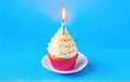 Festive cupcake with a candle on a blue background. With space for text