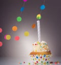 Festive cupcake with candle on grey background with garland