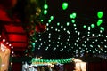 Festive dark blurred background with bokeh lights, electric garland. Garlands of lamps on a wooden stand on the street. Royalty Free Stock Photo
