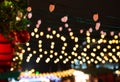 Festive dark blurred background with bokeh lights, electric garland. Garlands of lamps on a wooden stand on the street. Royalty Free Stock Photo