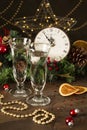 Festive decorated Christmas table with two glasses of champagne, old clock with decorations, fir branches with pine cones, festive Royalty Free Stock Photo