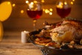 Festive dinner with baked turkey, red wine and lighted candle on wooden background with yellow lights. Traditional recipe for