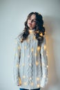 Festive dreaming woman portrait wrapped in Christmas lights. Royalty Free Stock Photo