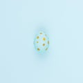 Festive easter background - blue easter egg with golden glitter dots on blue backdrop, square. Royalty Free Stock Photo