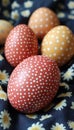 Festive Easter eggs decorated with white dots rest on blue fabric adorned with daisy pattern. Royalty Free Stock Photo