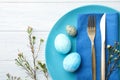 Festive Easter table setting with eggs and floral decoration on wooden background, flat lay Royalty Free Stock Photo