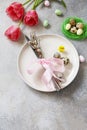 Festive Easter table setting with painted eggs, spring flowers and cutlery on light grey tabletop. Table setting for Happy Easter Royalty Free Stock Photo