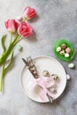 Festive Easter table setting with painted eggs, spring flowers and cutlery on light grey tabletop. Table setting for Happy Easter Royalty Free Stock Photo