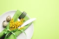 Festive Easter table setting with quail eggs and floral decor on green background, top view. Space for text Royalty Free Stock Photo