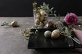 Festive Easter table setting with quail eggs and floral decoration on dark background Royalty Free Stock Photo