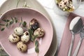 Festive Easter table setting with quail eggs and floral decoration on wooden background Royalty Free Stock Photo