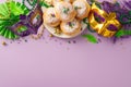 A top view of lively table featuring carnival masks, feathers, fan, and beads garlands. Sweet donuts add purple Royalty Free Stock Photo