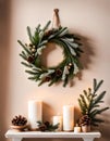 Festive fir wreath on a beige wall with white candles on a wooden shelf