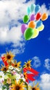 festive flowers and bright multi-colored inflatable balls against the background of the sky with clouds