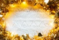 Festive frame made of gold garland with lights and tinsel on a white knitted with a pattern background, copyspace. New year, Royalty Free Stock Photo