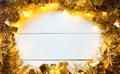 Festive frame made of gold garland with lights and tinsel on a white wooden background, copyspace. New year, Christmas, autumn and Royalty Free Stock Photo