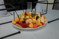 Festive fruits plate with cut fruit pieces on skewers in white plate. Dessert for birthday party, sweet appetizer. Banana, apple,