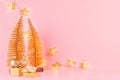 Festive gentle New Year background with glitter glossy gold decorations, Christmas tree, glowing stars lights on pink backdrop. Royalty Free Stock Photo