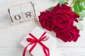 A festive gift, a bouquet of red roses and a gift box on a wooden background. The concept of congratulations on March 8 or wooman Royalty Free Stock Photo