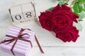A festive gift, a wooden calendar, bouquet of red roses and a gift box on a wooden background. The concept of congratulations on Royalty Free Stock Photo