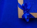 Festive gift wrapped present box with blue satin bow close up isolated on trendy blue background Royalty Free Stock Photo