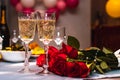Festive glasses with sparkling champagne on the table of the newlyweds with a bouquet of red roses, selective focus, wedding Royalty Free Stock Photo