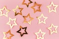 Festive gold glossy stars on pastel pink background, top view, pattern.