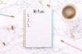 Festive golden stationary and coffee on white marble background. My Plans wording. Copy space