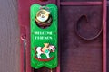 Festive green welcome friends Christmas Card with rocking horse on red door with gold door knob