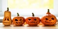 Festive scary halloween pumpkins on a wooden table in front of a window