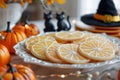 Festive Halloween Table Setting with Decorative Pumpkins, Witch Hat, Black Cats, and Iced Orange Slice Cookies