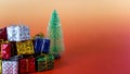 Colorful Christmas gift boxes with green decorative tree on vibrant gradient background Royalty Free Stock Photo