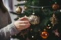 Festive Holiday Magic Hands Decorating Christmas Tree with Stylish Bauble in Atmospheric Room. created with Generative AI Royalty Free Stock Photo