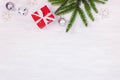 festive holiday white wooden background with green christmas tree branch, glass balls, snowflakes and red handmade gift box with Royalty Free Stock Photo