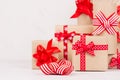 Festive home decor with many kraft gift boxes with red ribbons on white wood board, copy space, closeup.